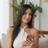 uma_mulher_sorridente_sentada_de_forma_casual_em_um_sof_claro_em_um_ambiente_interno_iluminado_natu_9c2w6a1rfu5umxtaryik_0
